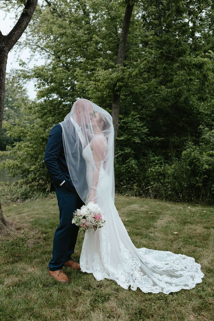 Bride and groom kiss while enveloped in the bride's veil