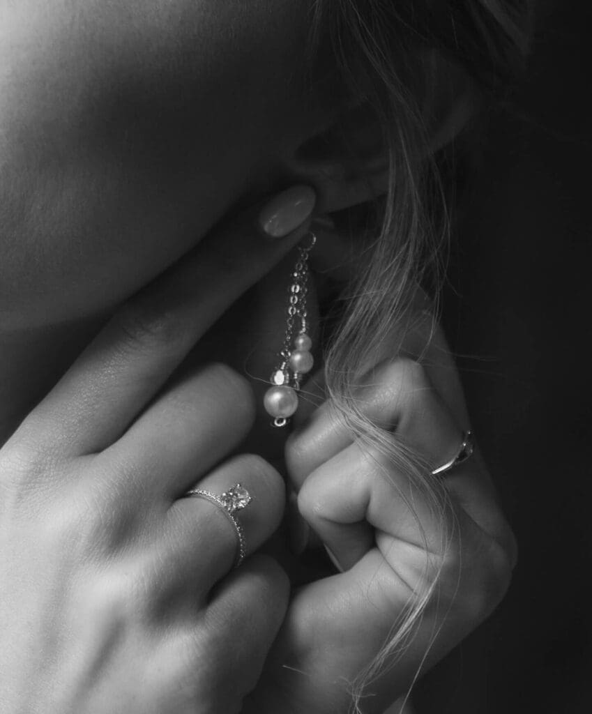 Close up of bride putting on pearl earrings on her wedding day