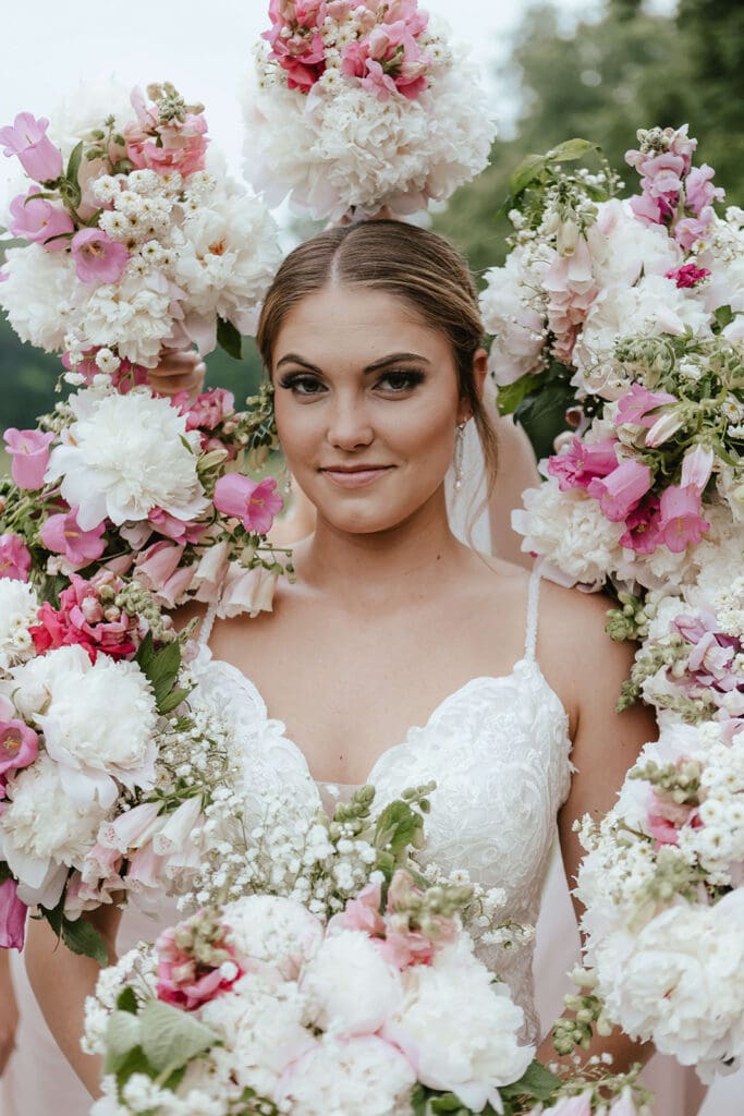 Close up of bride's face surrounded by bridesmaids' white and pink bouquets