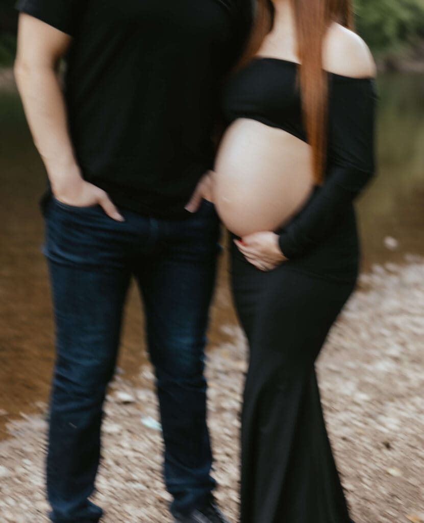 Purposely blurred outdoor maternity photo closeup of couple's hands and woman's belly