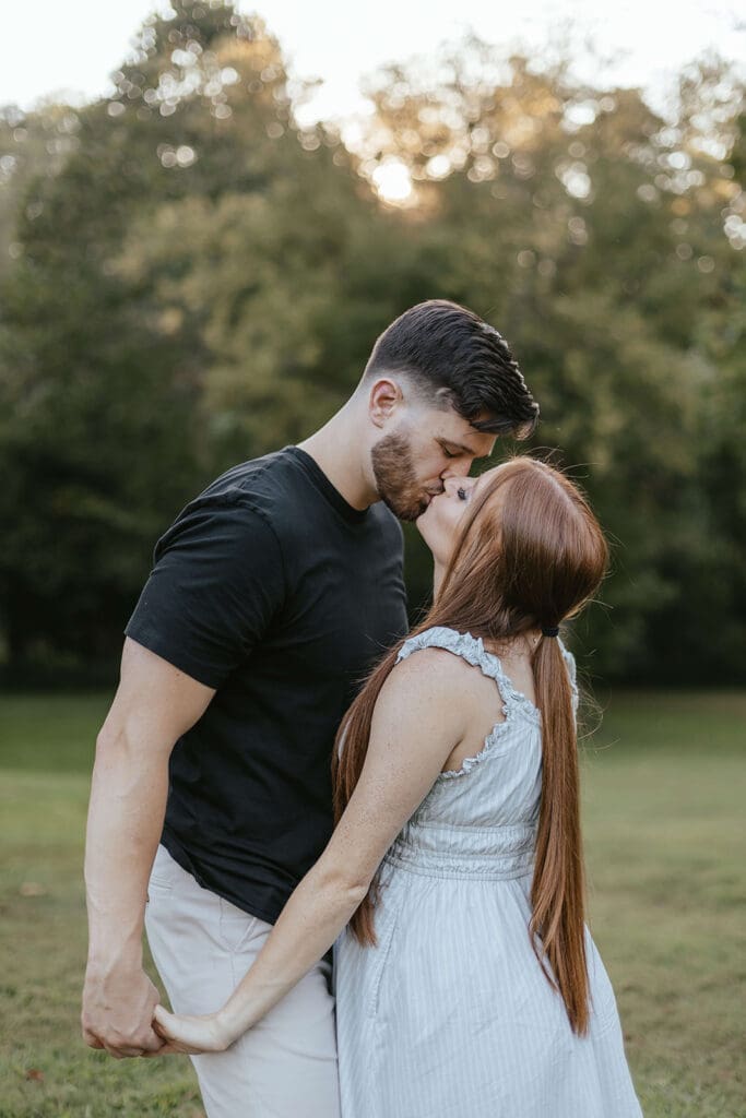 Man and woman share a kiss during their outdoor maternity photo shoot in Lancaster