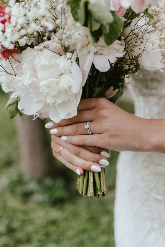 Close up image of bride wearing wedding ring, holding her bouquet