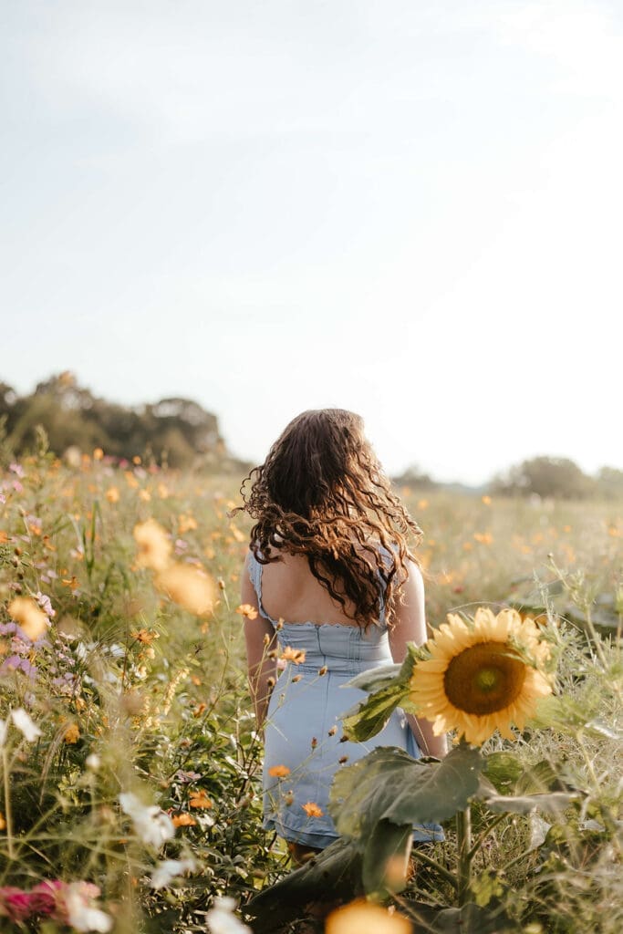 Senior portrait of a girl in a blue dress in a field of wildflowers