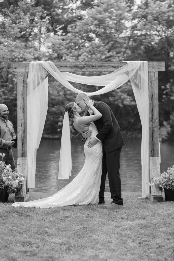 Bride and groom share first kiss during their intimate wedding ceremony by a creek