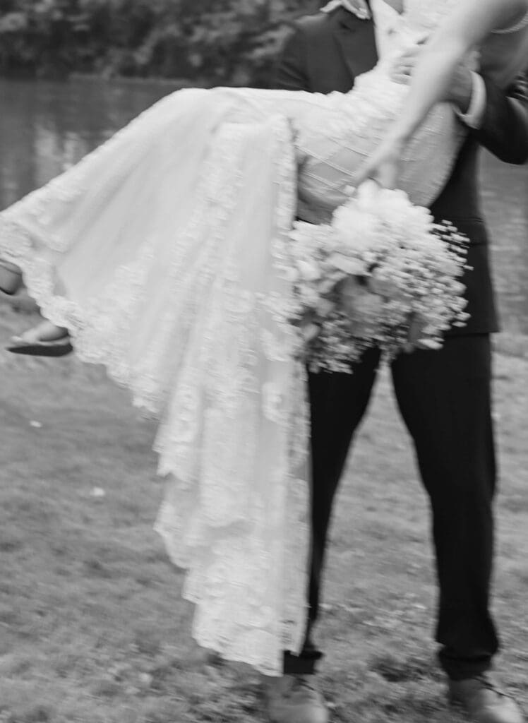 Purposely blurred photo featuring groom carrying bride while holds her wedding bouquet