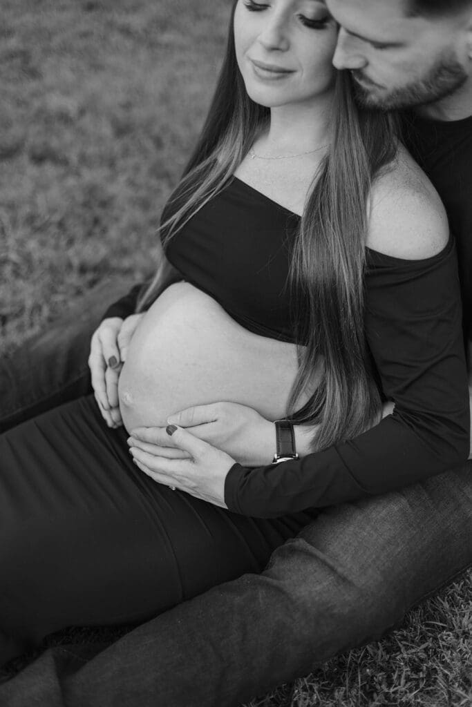 Woman sits with man and both embrace woman's pregnant belly