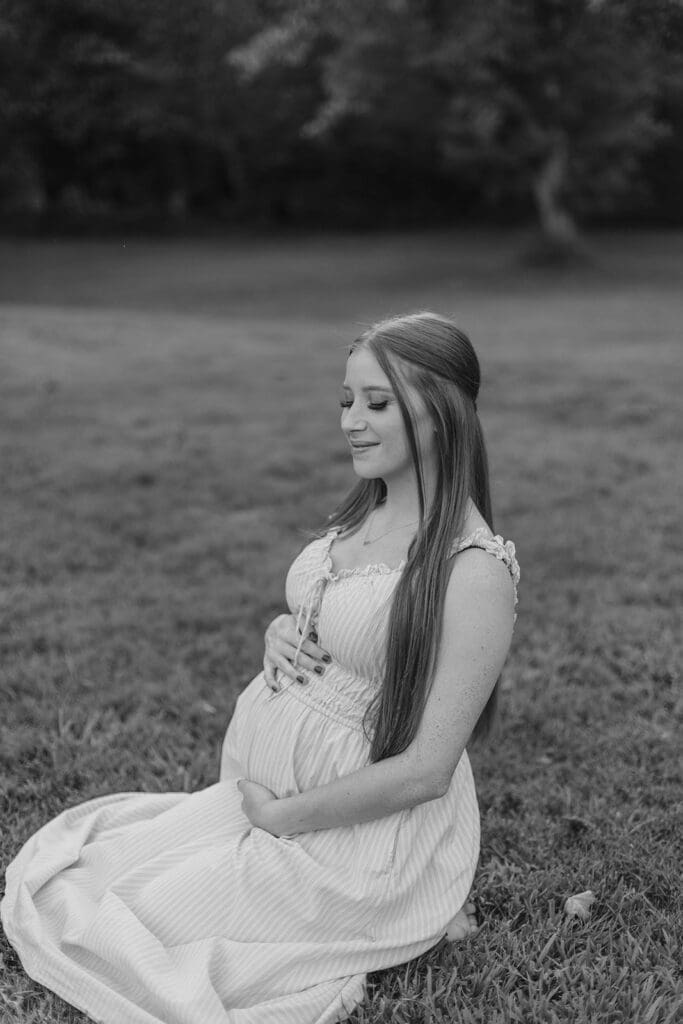 Maternity portrait of woman smiling and sitting in a field