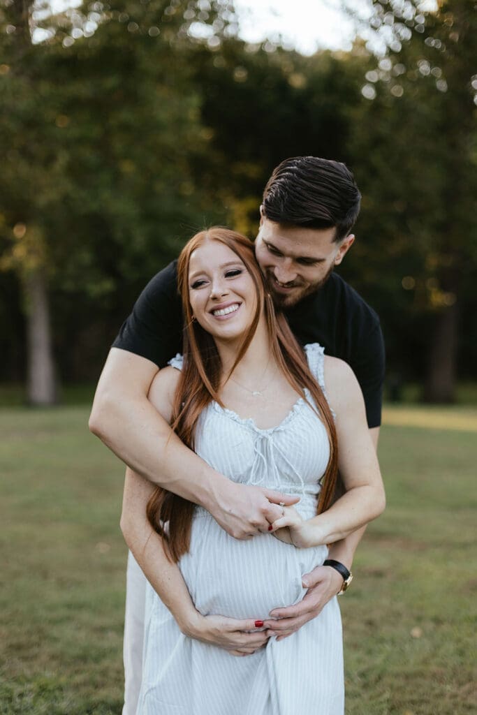 Man embraces woman from behind and holds her stomach