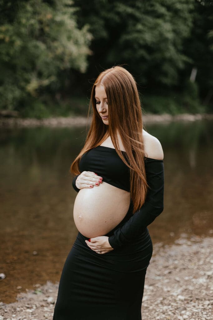 Portrait of a pregnant woman looking down and touching her belly
