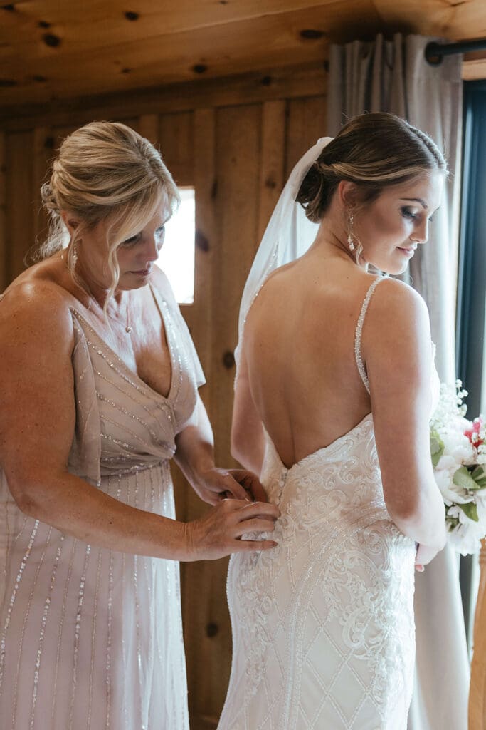 Mother of bride fastens the bride's wedding dress