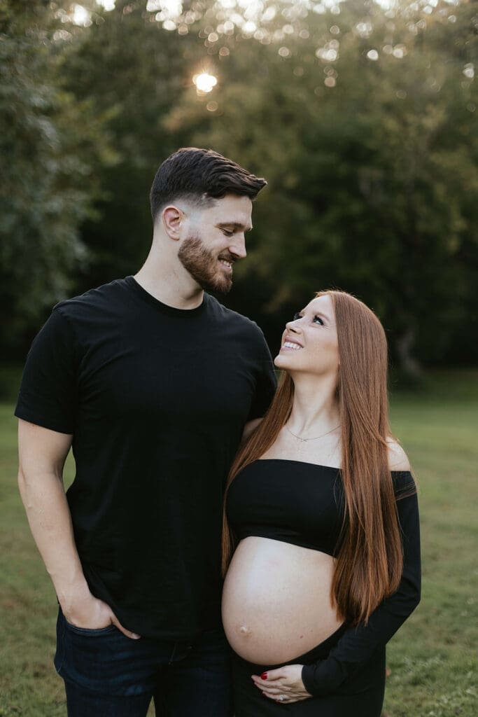 Man and woman smile at each other during their maternity photos in Lancaster County Central Park