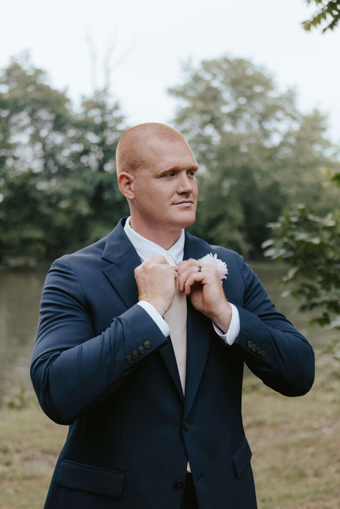 Portrait of the groom fixing his tie outdoors