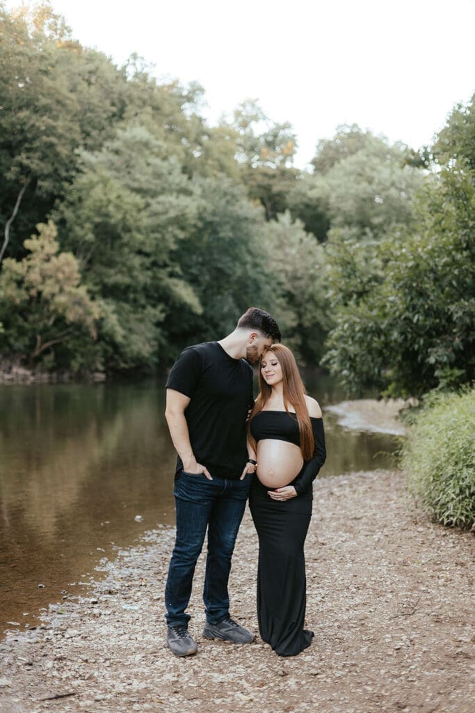 Portrait of a pregnant woman and her husband on the banks of a creek in Lancaster County Central Park