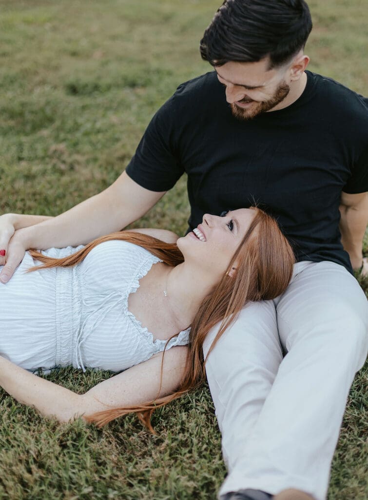 Woman lays her head on her husband's lap and smiles at him