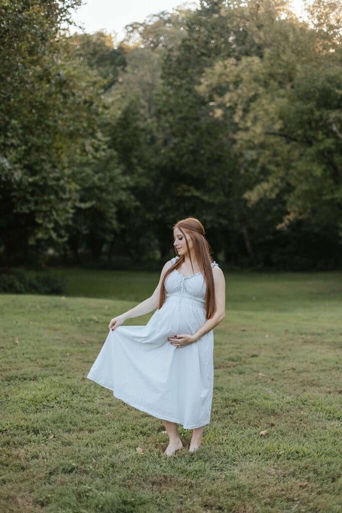 Woman wearing a romantic summer dress touches her pregnant belly