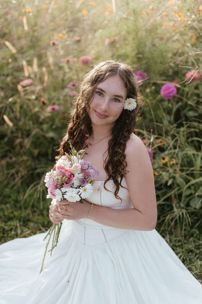Senior portrait of girl holding bouquet with daisy tucked behind her ear