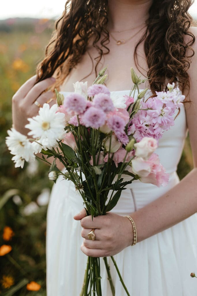 Girl wearing gold jewelry holds a bouquet of flowers