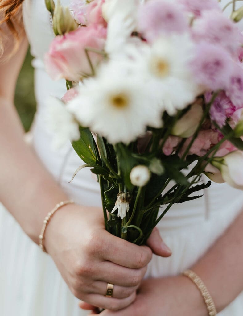 Girl wearing gold jewelry holds a bouquet of flowers