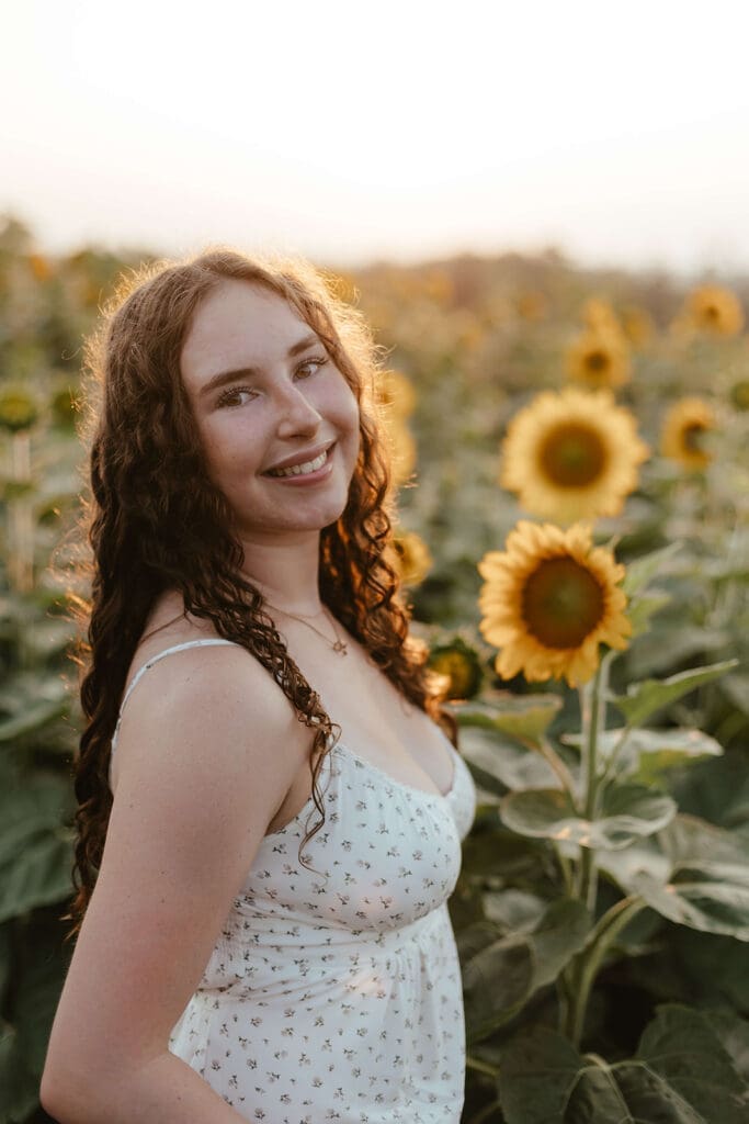 Senior portrait in a golden field of sunflowers
