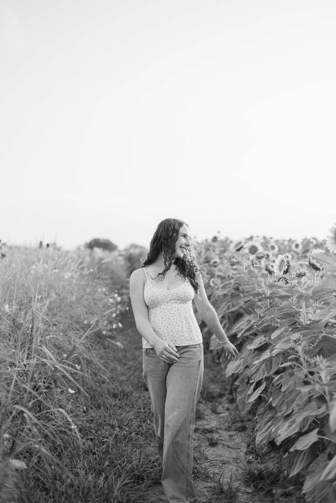 Girl walks through a field of wildflowers wearing a white tank top and jeans
