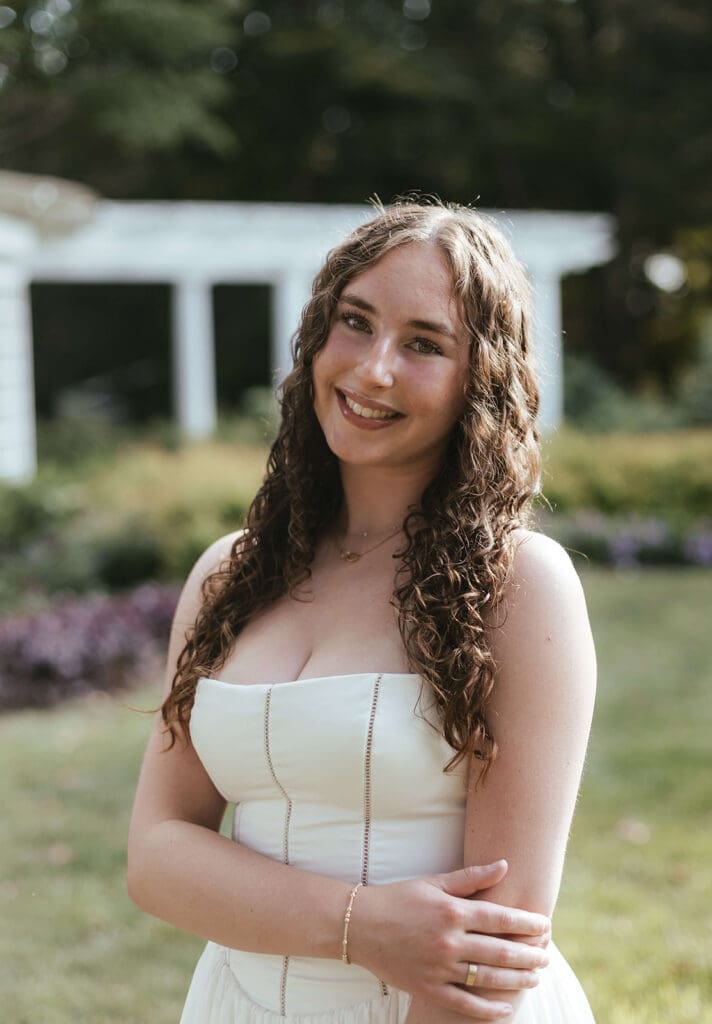Portrait of senior in a feminine white dress and gold jewelry
