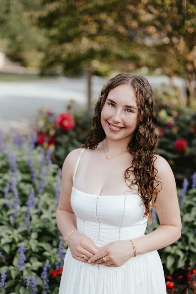 Senior portrait of girl smiling in front of a garden of flowers