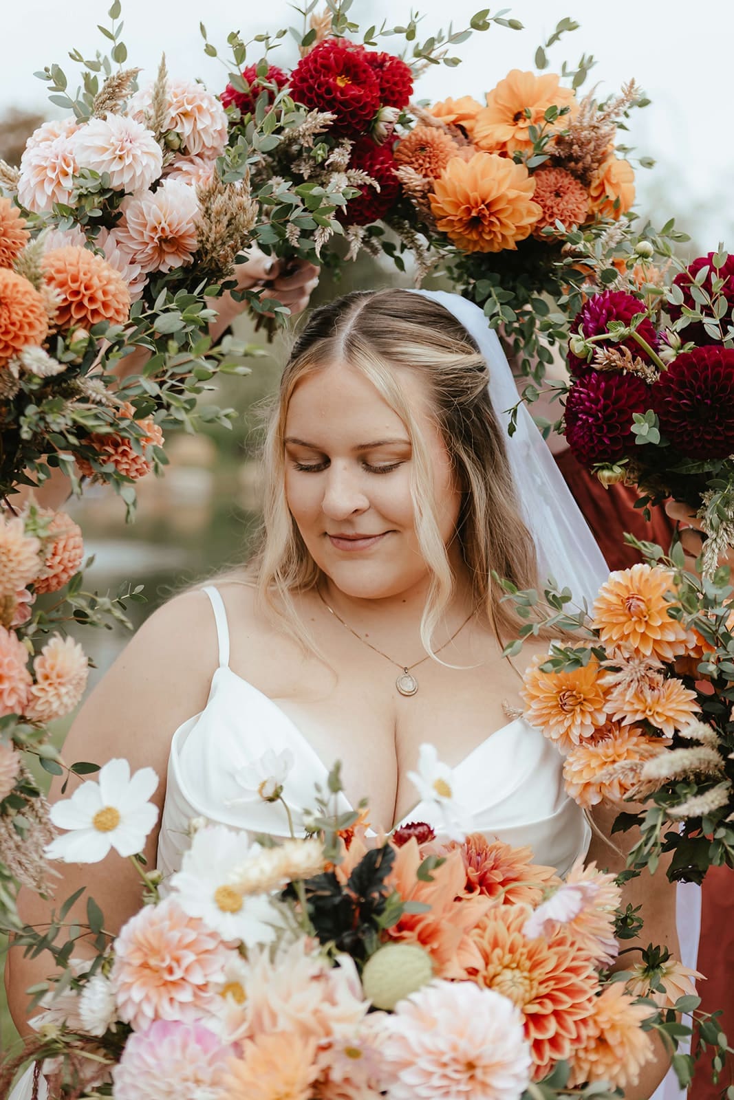 Portrait of bride surrounded by wedding bouquets in earthy fall colors