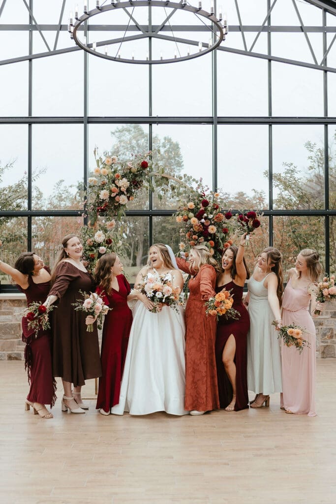 Bride with bridesmaids wearing fall colors in a greenhouse