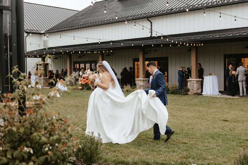 Bride and groom walking outdoors during their rainy fall cocktail hour