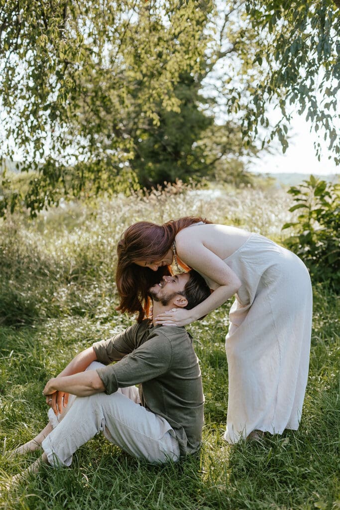 Woman leans over fiancé, ready to kiss him in a field in Pennsylvania