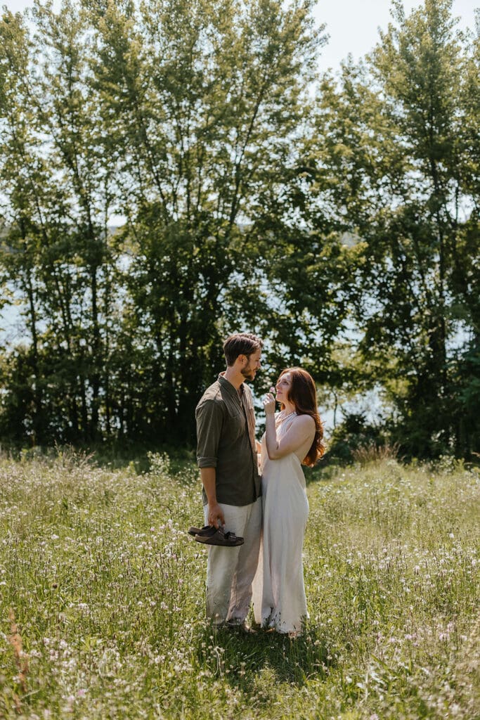 Man and woman gaze at each other in an open field during their summer engagement photos in Pennsylvania