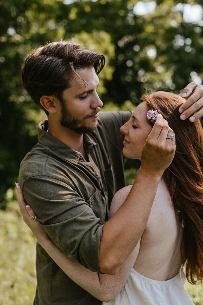 Up close shot of man tucking a flower behind his fiancée's ear