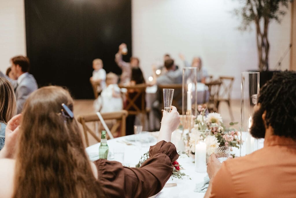 Wedding guest lifting glass to toast during speeches