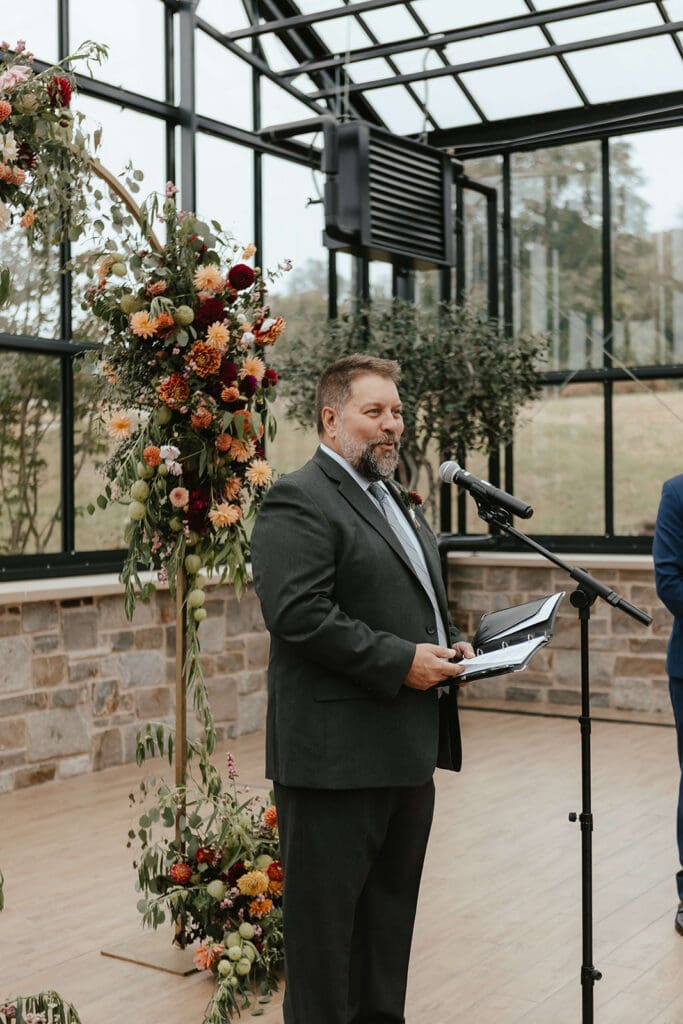Bride's father officiating the greenhouse wedding ceremony