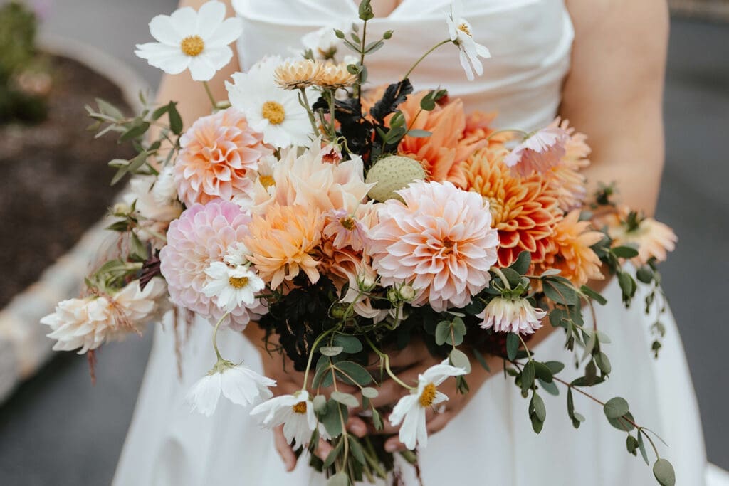 Bridal bouquet with orange and light pink flowers, and greenery
