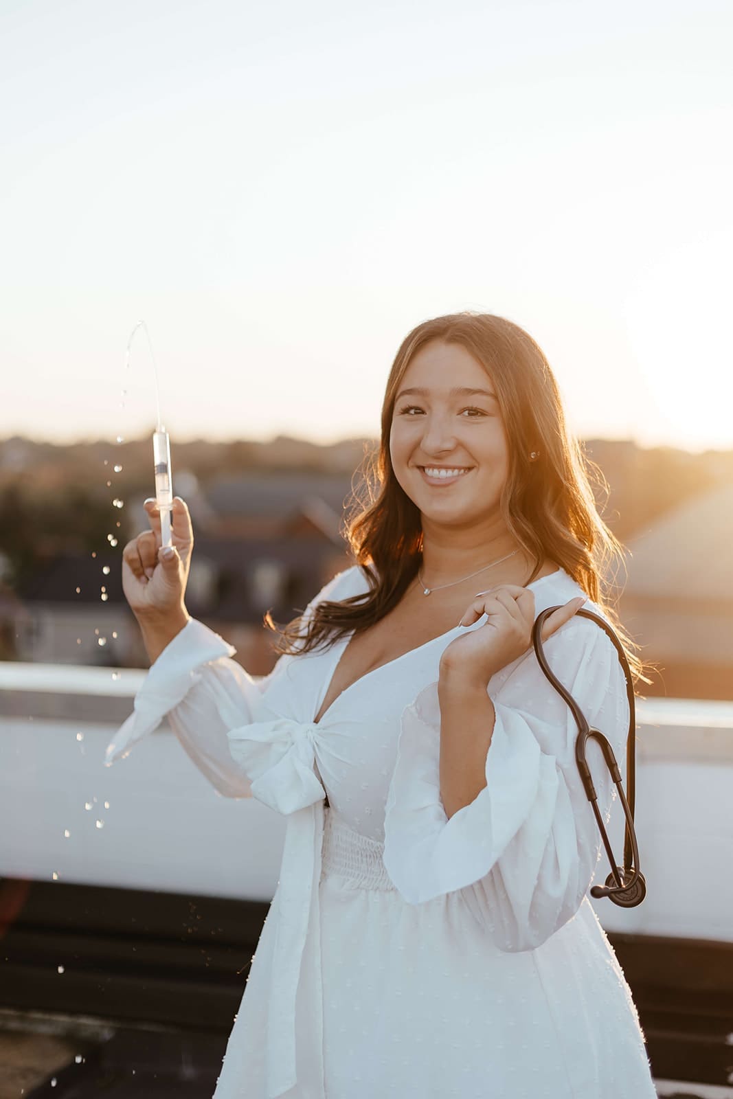 Nursing student holding syringe and stethoscope for her graduation photo session