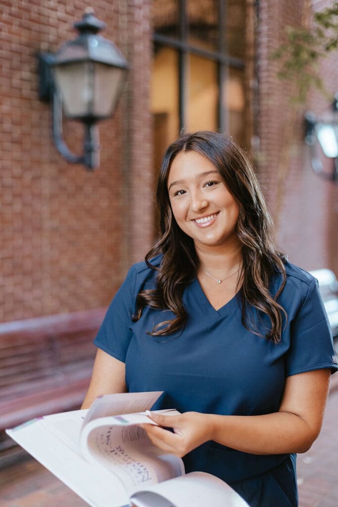 Nursing student in scrubs opening medical textbook in downtown Lancaster City