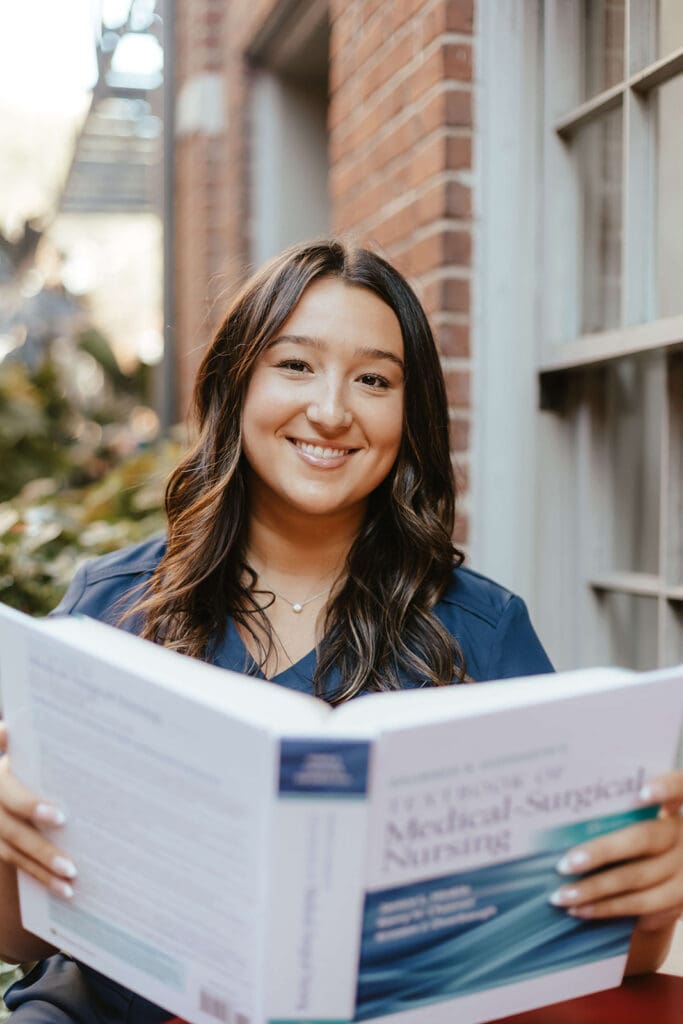 Portrait of nursing student in scrubs with her textbook in downtown Lancaster City